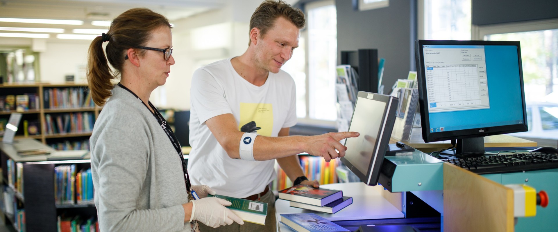 Kirjaston työntekijä opastaa asiakasta lainausautomaatin käytössä Kärpäsen lähikirjastossa Lahdessa.