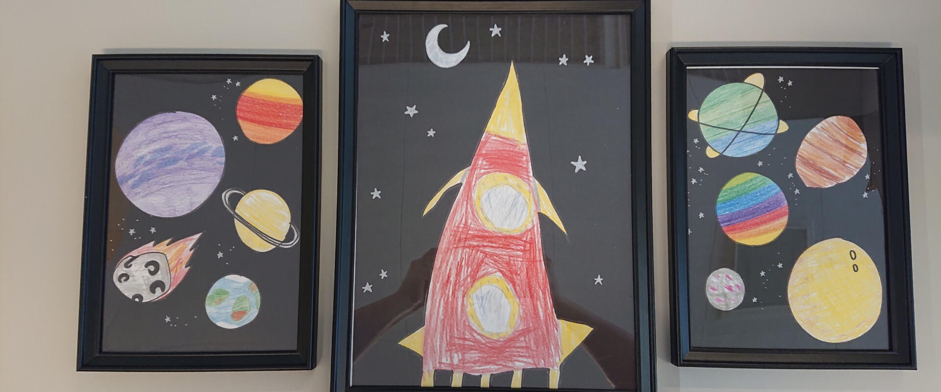 Kolme lapsen piirtämää avaruustaulua.