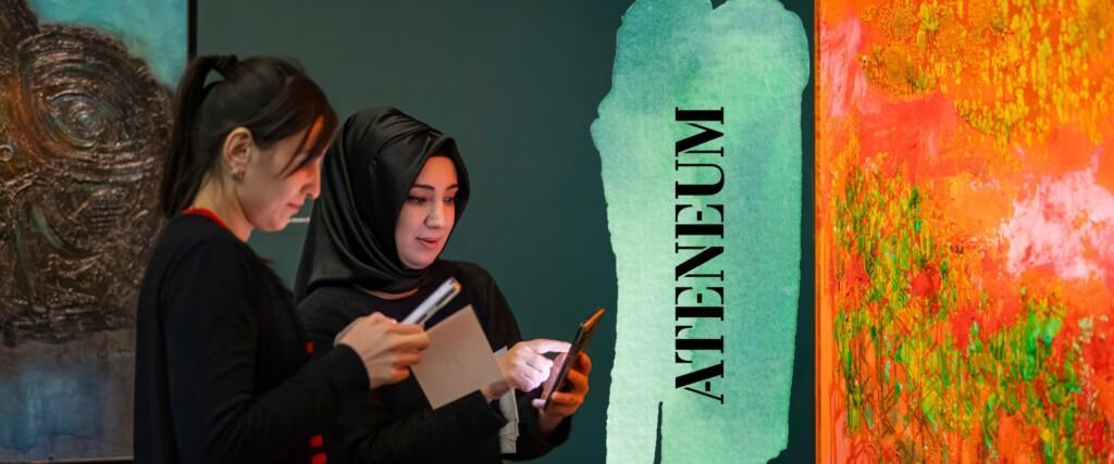 Taidemuseon kävijät seisovat Särestöniemen taideteoksen äärellä ja tutustuvat teokseen älylaitteiden avulla.